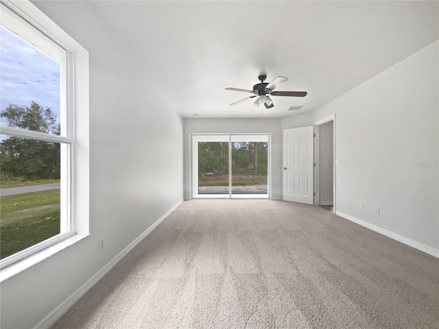 unfurnished room with ceiling fan, a wealth of natural light, and carpet