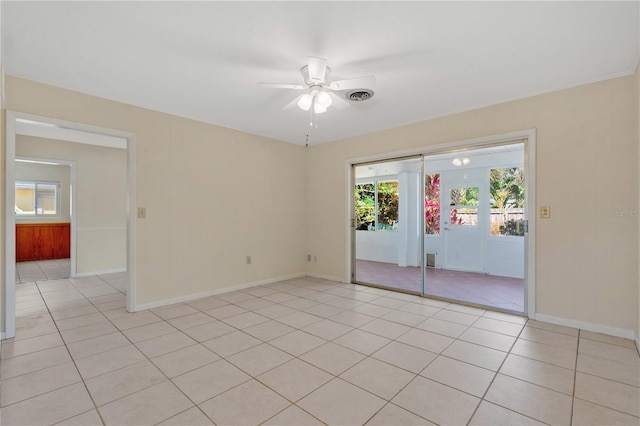 empty room featuring light tile patterned floors, baseboards, visible vents, and ceiling fan