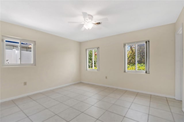 spare room featuring light tile patterned flooring, a ceiling fan, and baseboards