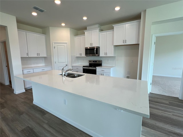 kitchen featuring an island with sink, sink, white cabinets, and electric stove