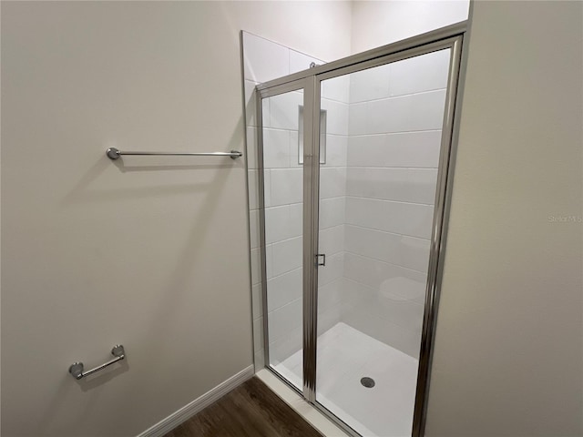 bathroom with a shower with shower door and hardwood / wood-style flooring