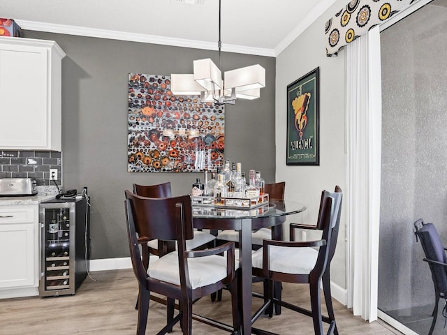 dining space featuring crown molding, an inviting chandelier, beverage cooler, and light hardwood / wood-style floors