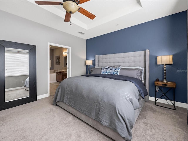 carpeted bedroom with connected bathroom, a raised ceiling, and ceiling fan