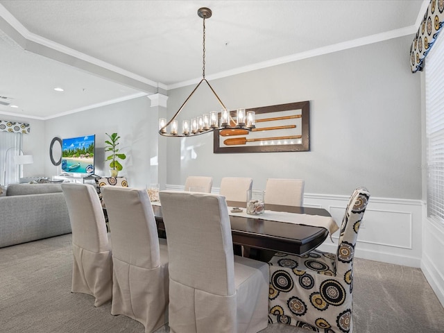 dining room with a notable chandelier, ornamental molding, and carpet