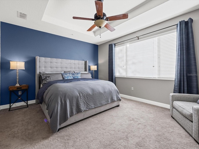 bedroom featuring ceiling fan, a raised ceiling, and carpet