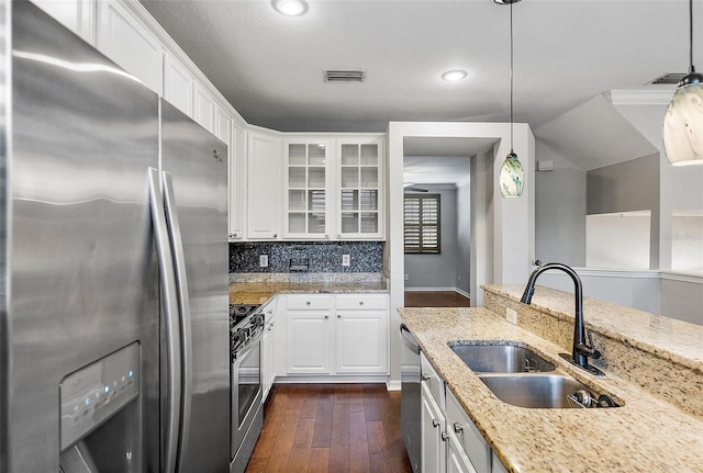 kitchen featuring stainless steel appliances, sink, white cabinets, and decorative light fixtures