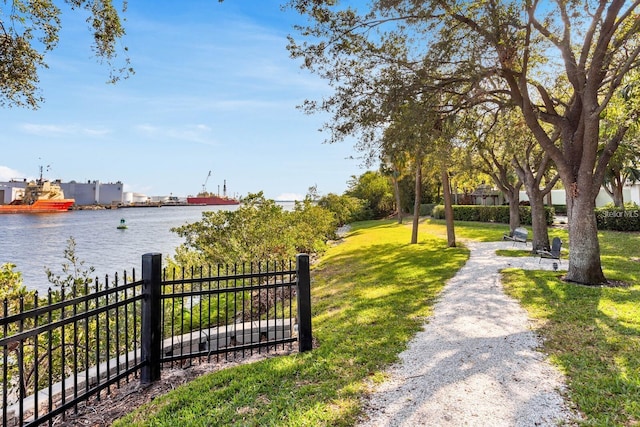 surrounding community with a water view and a lawn