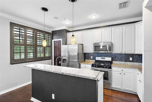 kitchen with white cabinetry, decorative light fixtures, a center island with sink, appliances with stainless steel finishes, and backsplash