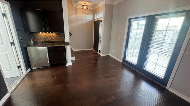 interior space with ornamental molding, dark hardwood / wood-style floors, stainless steel dishwasher, and backsplash