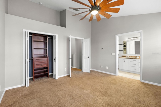 unfurnished bedroom with ceiling fan, ensuite bath, high vaulted ceiling, and light colored carpet