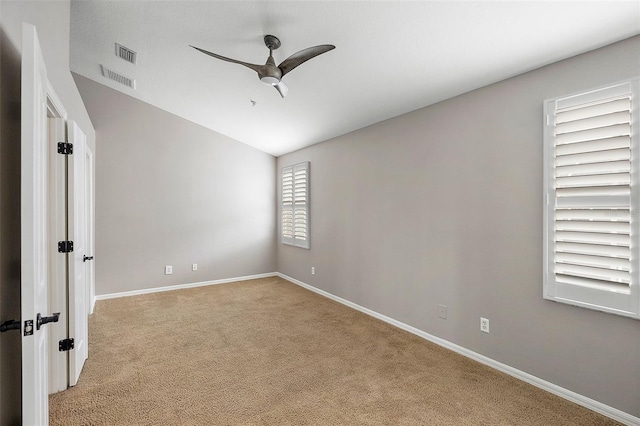 empty room with ceiling fan, vaulted ceiling, and light carpet