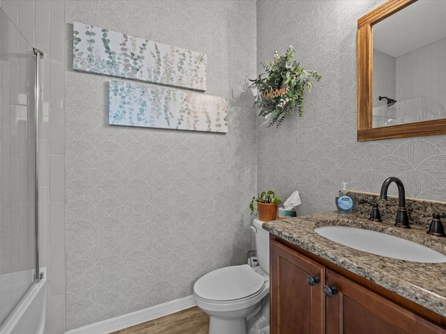 full bathroom with wood-type flooring, shower / bath combination with glass door, vanity, and toilet