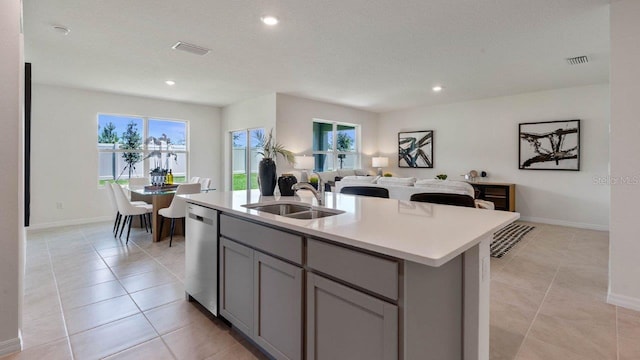 kitchen with dishwasher, gray cabinetry, an island with sink, light tile patterned floors, and sink