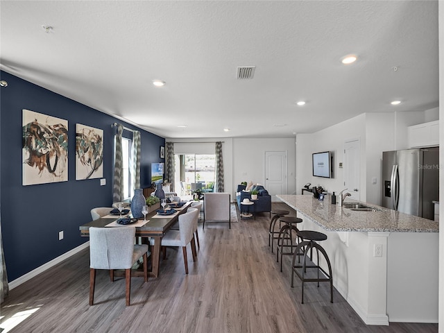 dining room featuring sink, a textured ceiling, and hardwood / wood-style flooring