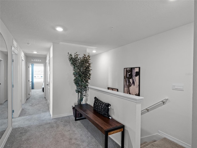 hallway featuring a textured ceiling and light colored carpet