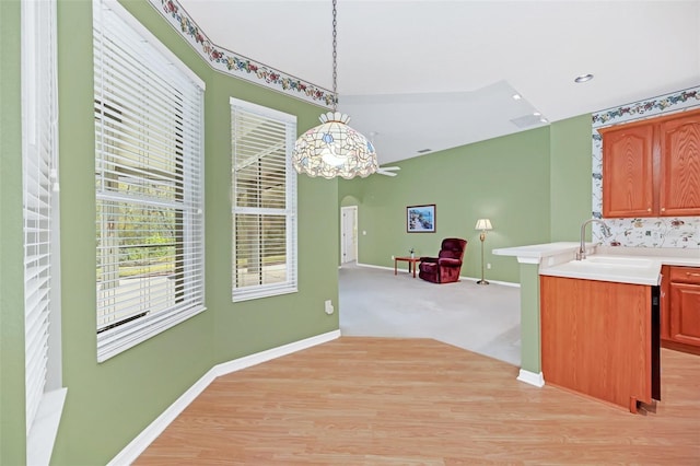 kitchen featuring pendant lighting, kitchen peninsula, sink, and light carpet