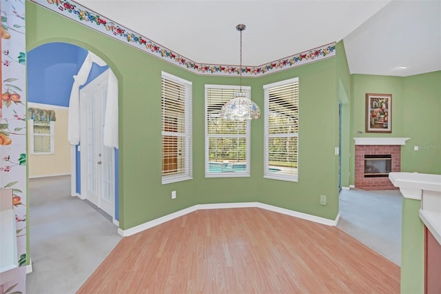 unfurnished dining area featuring a brick fireplace and light hardwood / wood-style floors