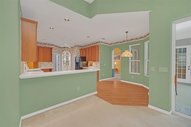 kitchen with decorative light fixtures, kitchen peninsula, decorative backsplash, and black fridge