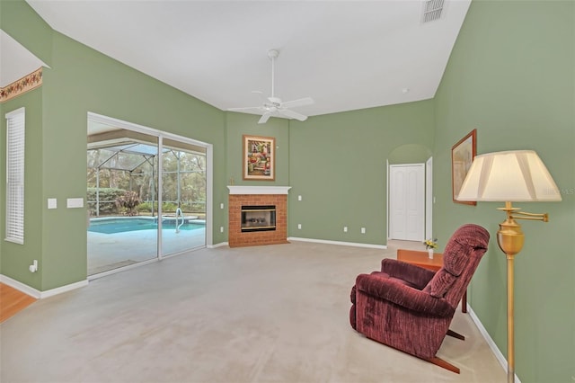 living area featuring a brick fireplace, carpet floors, and ceiling fan