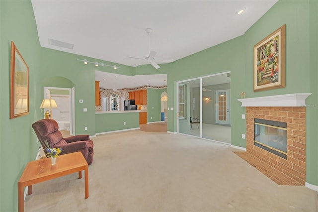 sitting room with ceiling fan, carpet flooring, and a brick fireplace