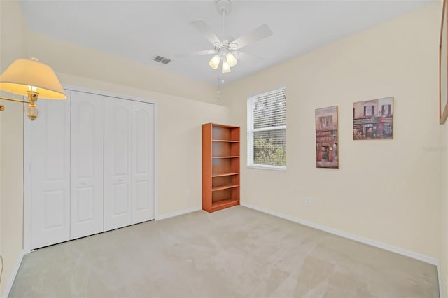 unfurnished bedroom featuring ceiling fan, light carpet, and a closet