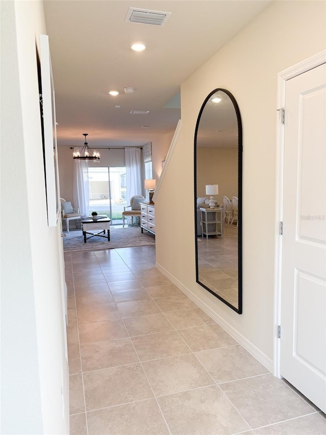 hall featuring a notable chandelier and light tile patterned flooring