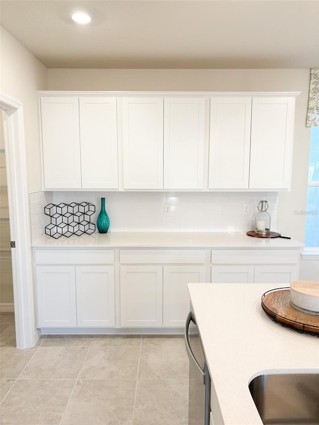 kitchen featuring decorative backsplash, white cabinetry, and stainless steel dishwasher