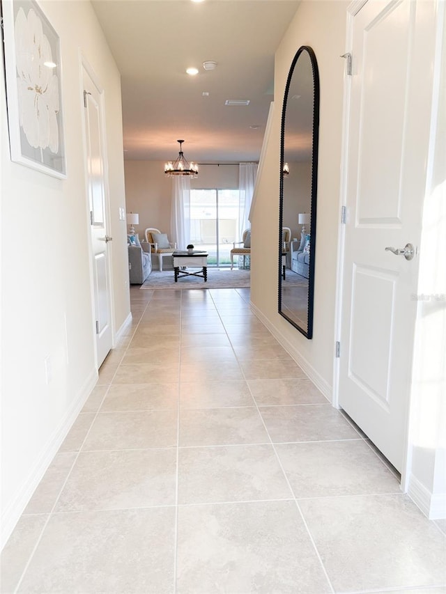 corridor featuring light tile patterned floors and an inviting chandelier