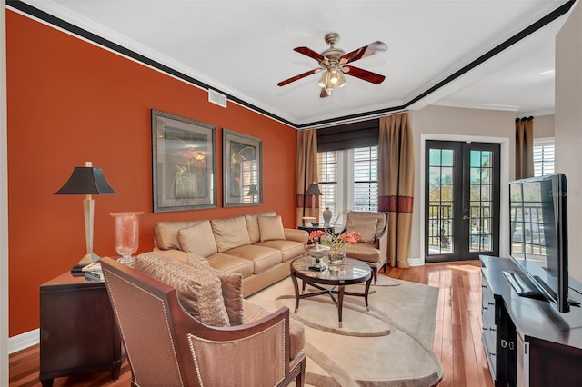 living room with ceiling fan, crown molding, light hardwood / wood-style flooring, and french doors