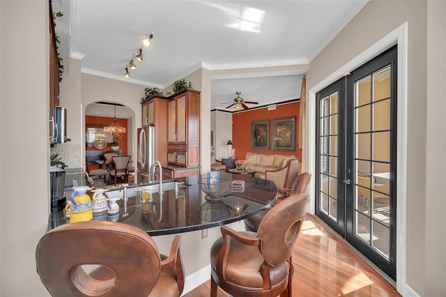 dining room featuring french doors, crown molding, ceiling fan with notable chandelier, light hardwood / wood-style flooring, and sink