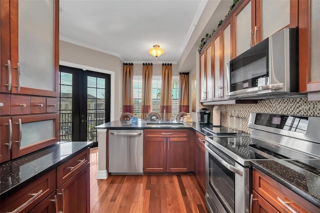 kitchen featuring appliances with stainless steel finishes, a barn door, hardwood / wood-style floors, and dark stone counters