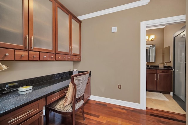 office featuring built in desk, dark wood-type flooring, and crown molding