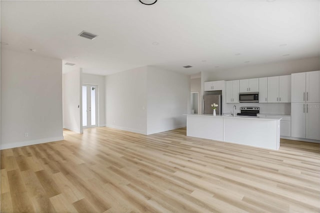 kitchen featuring a kitchen island with sink, appliances with stainless steel finishes, light hardwood / wood-style floors, sink, and white cabinetry