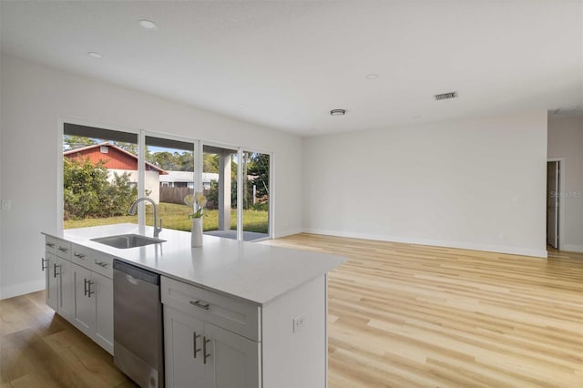 kitchen with sink, an island with sink, dishwasher, and light wood-type flooring