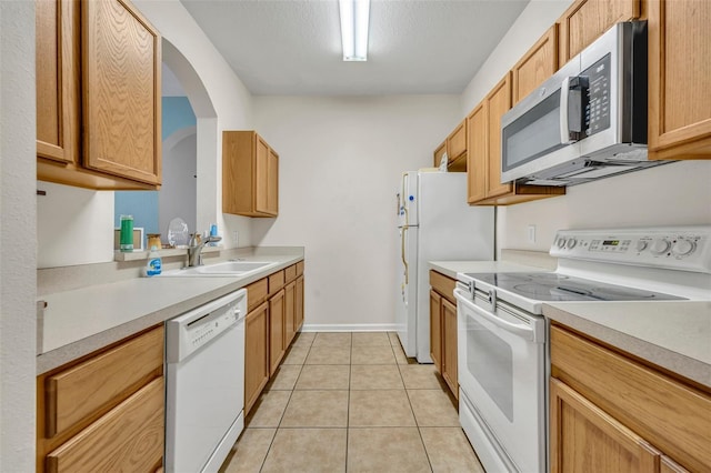 kitchen featuring sink, white appliances, light tile patterned floors, and a textured ceiling