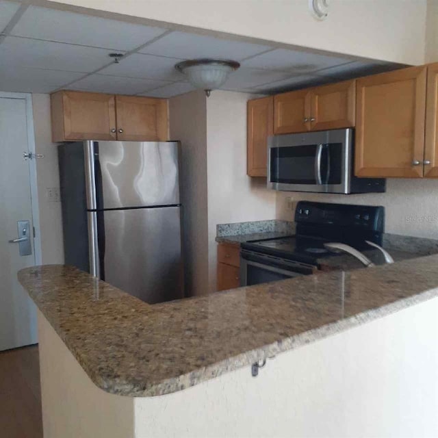 kitchen with stainless steel appliances, a paneled ceiling, and kitchen peninsula