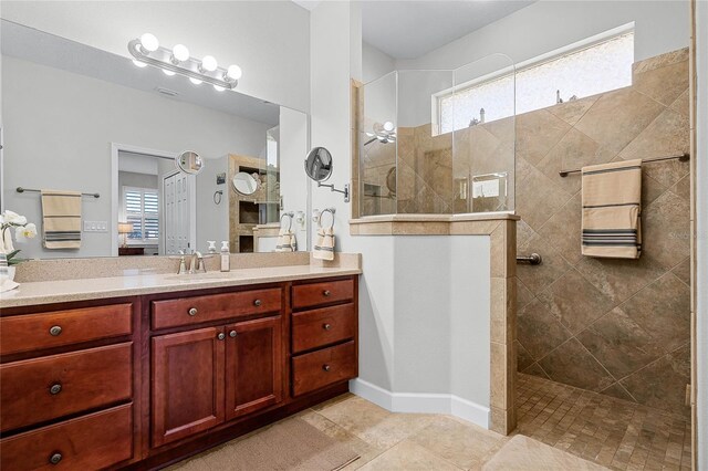 bathroom with tile patterned flooring, vanity, plenty of natural light, and a tile shower