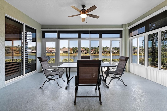 sunroom featuring ceiling fan and a water view