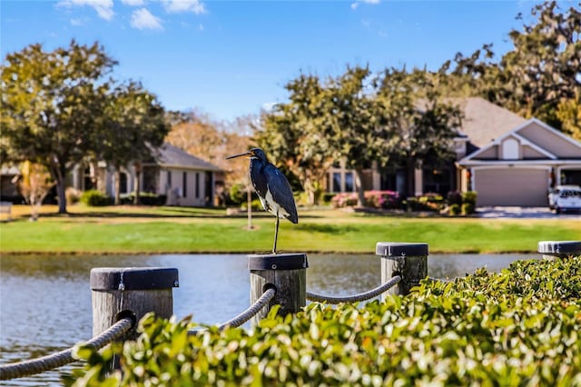 exterior space featuring a garage, a lawn, and a water view