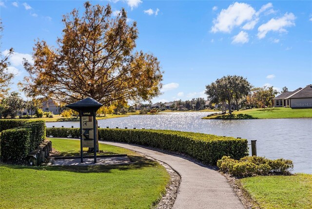 view of property's community with a lawn and a water view