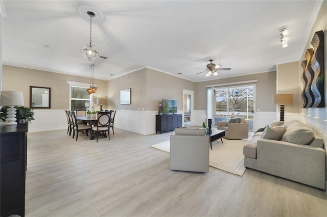 living room with ceiling fan, ornamental molding, and light wood-type flooring