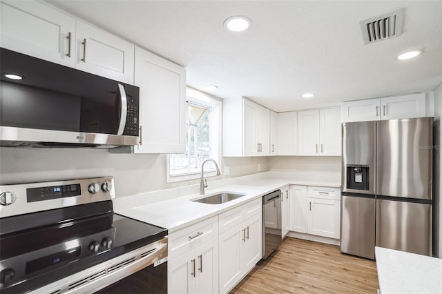 kitchen with light hardwood / wood-style flooring, stainless steel appliances, white cabinets, and sink