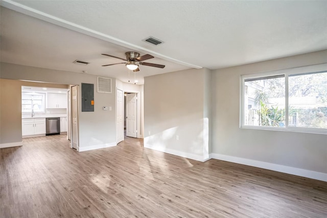 unfurnished living room with sink, light wood-type flooring, ceiling fan, and electric panel