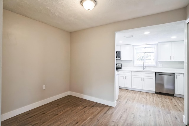 kitchen featuring sink, stainless steel appliances, white cabinetry, and light wood-type flooring