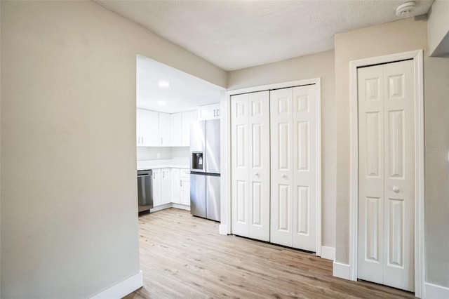 kitchen featuring stainless steel appliances, white cabinetry, and light hardwood / wood-style flooring