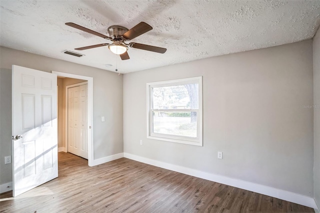 unfurnished room with a textured ceiling, ceiling fan, and light wood-type flooring