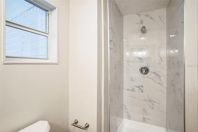 bathroom featuring a tile shower and toilet