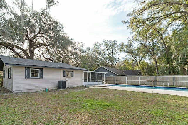 back of property featuring central AC, a yard, a sunroom, and a fenced in pool