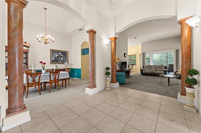 interior space with a towering ceiling, a chandelier, and ornate columns