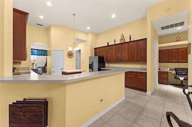 kitchen with a notable chandelier, stainless steel refrigerator with ice dispenser, light tile patterned flooring, a high ceiling, and hanging light fixtures